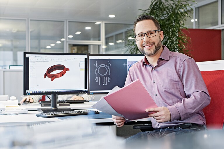 Mann vor Bildschirmen mit CAD-Grafiken.