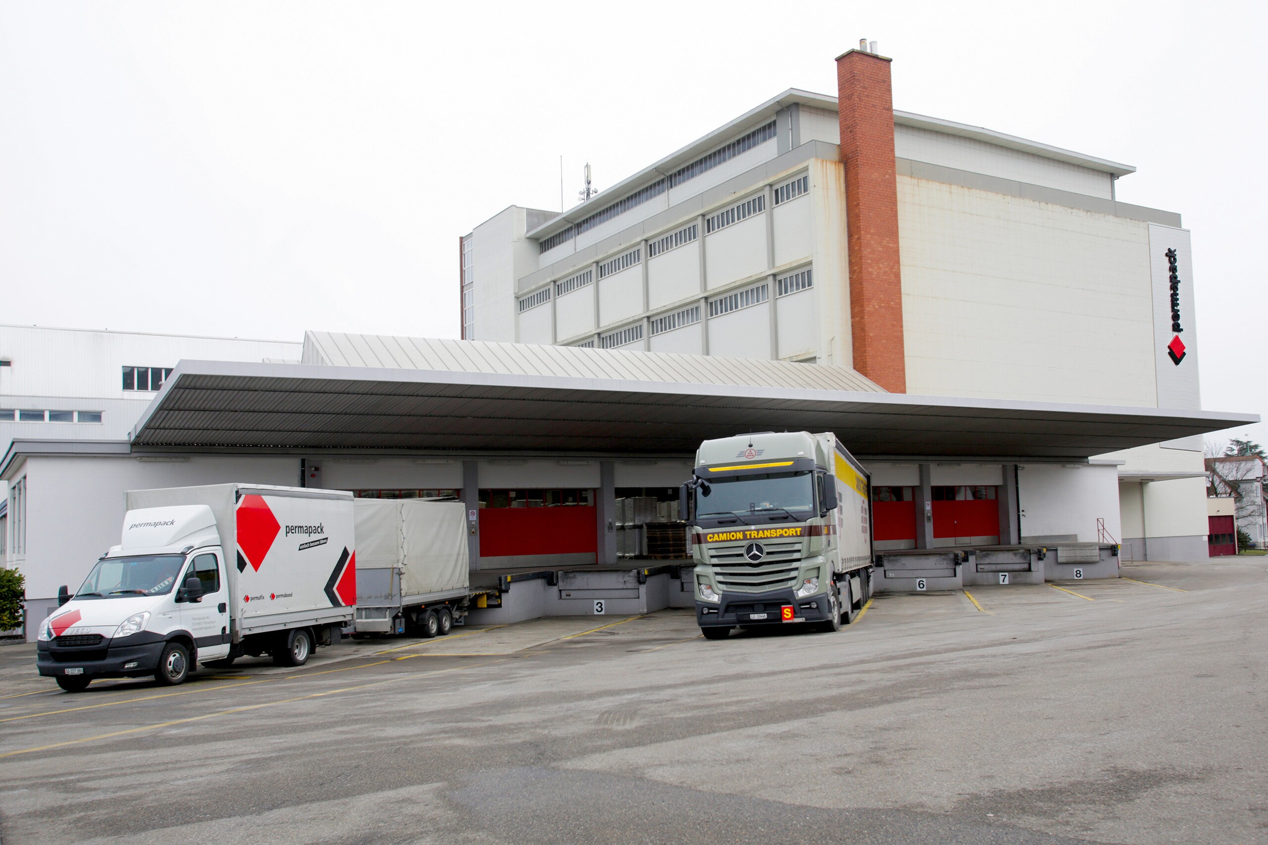 Logistikgebäude mit Lastwagen an Laderampen