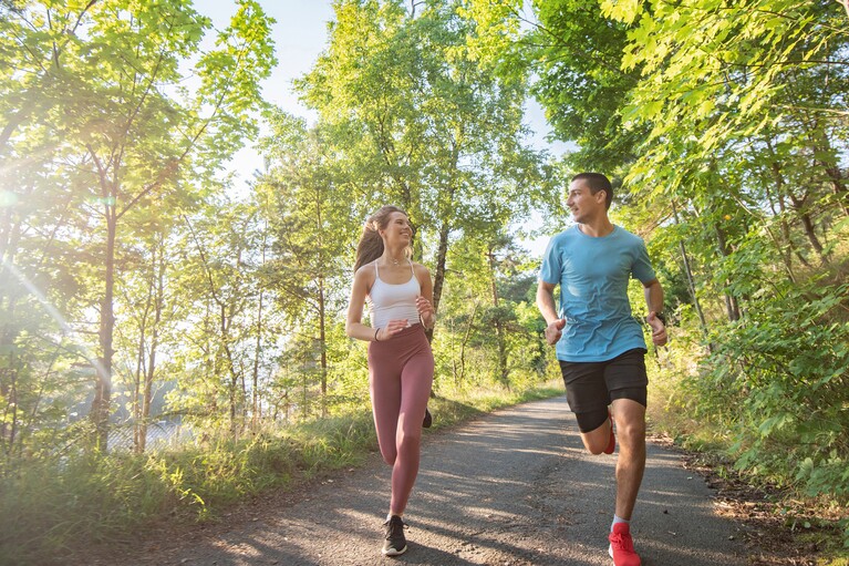 Une femme et un homme s'entraînant à la course à pied dans la forêt