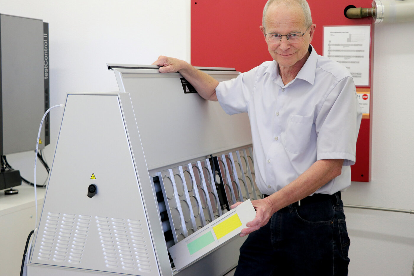 Ein Mann steht neben einer Prüfanlage für Klebebänder