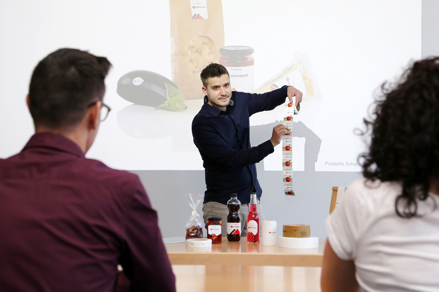 Drei Personen bei einer Kundenschulung über Etiketten, Klebebänder und Beutel.