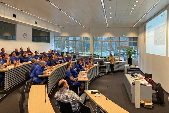 Rund 30 Produktionsmitarbeitende sitzen in einem Schulungsraum und blicken interessiert auf eine Leinwand.
