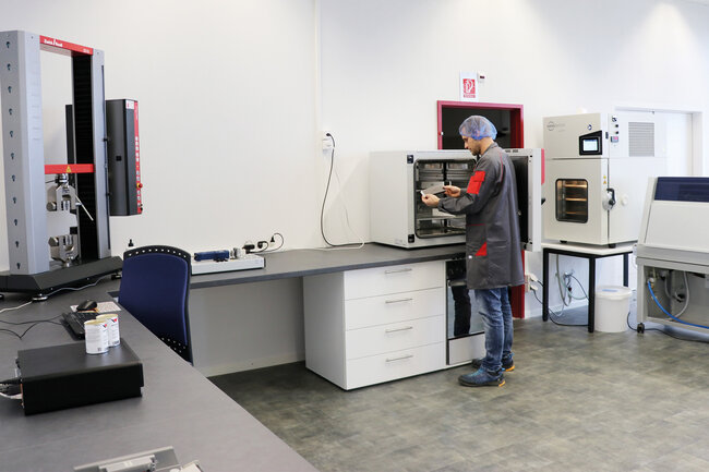 Permapack-Mitarbeiter betrachtet Teststück im Labor. 