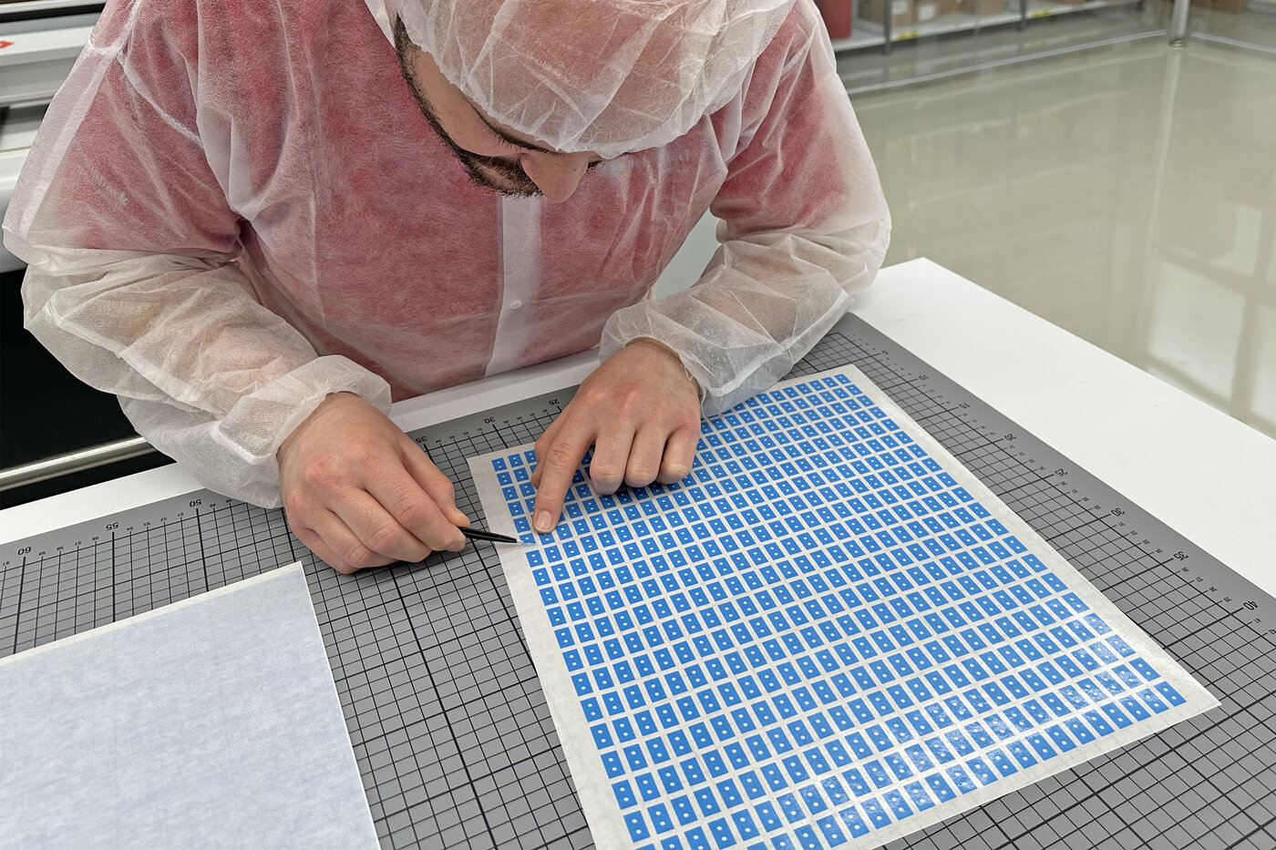 Mann mit Stanzteilen vor Plotter-Maschine