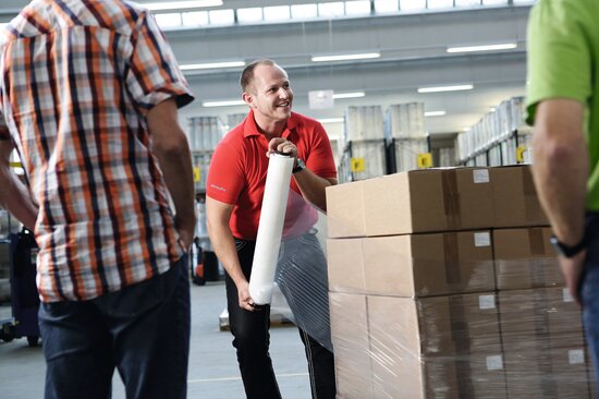 Mann umwickelt Palette mit Kartons mit einer Handstretchfolie