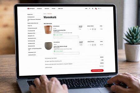 Person bestellt über einen Laptop Pflanzengefässe im Permapack Online-Shop
