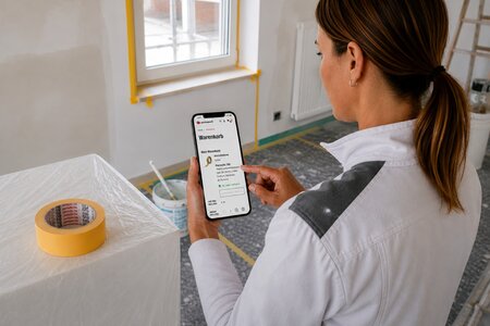 Eine Malerin bestellt ein Washi Abdeckband auf der Baustelle per Smartphone nach