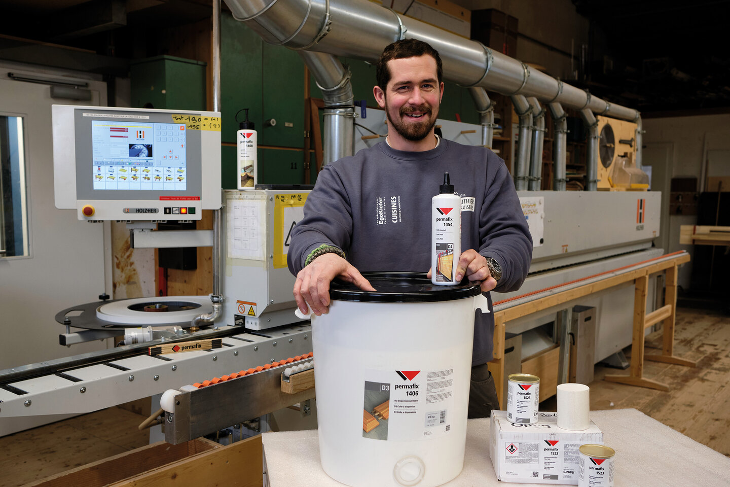 Produktionsleiter steht vor Produktionsanlage mit Permafix Holzklebstoffen auf Tisch