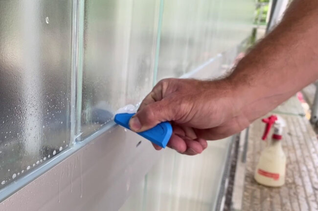 Mann glättet Dichtstoff-Fuge mit einem Werkzeug