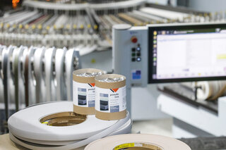 Zwei Dosen Schmelzklebstoffe stehen auf ein paar Rollen Kantenbänder.