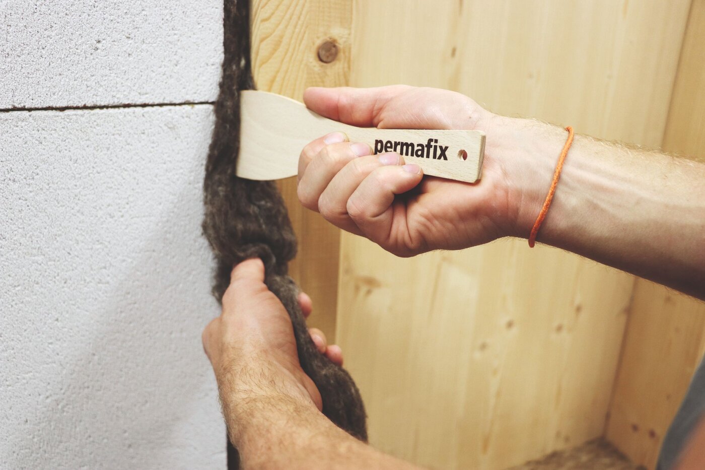 Ein Handwerker stopft ein Fugenzopf Permafix 606 mit einem Spachtel in eine Fuge zwischen Beton und Holz