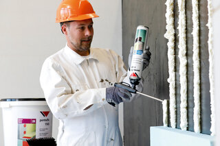 Arbeiter trägt Permafix Dosenschaum an Wand auf