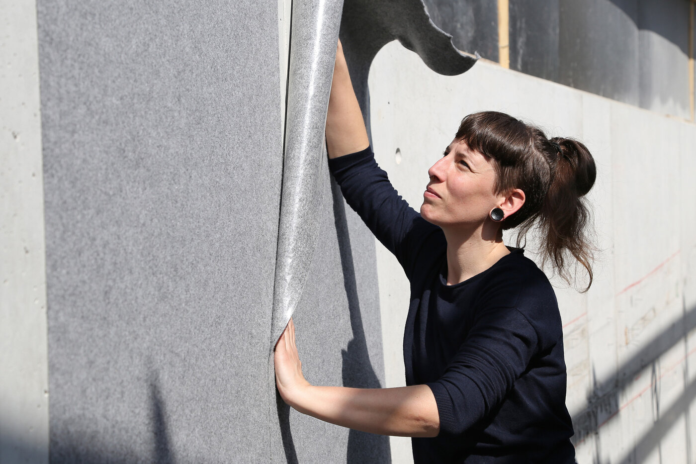 Malerin verlegt das selbstklebende Schutzvlies Allfelt 1130 an einer Wand