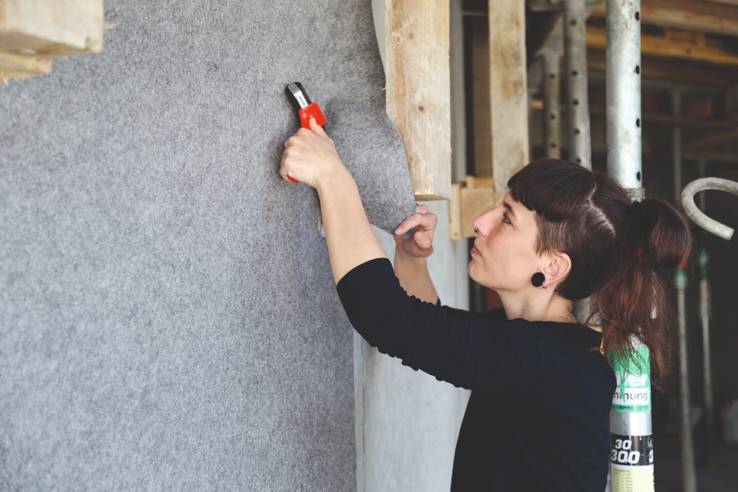 Eine Malerin verlegt das selbstklebende Schutzvlies Allfelt 1130 an einer Wand