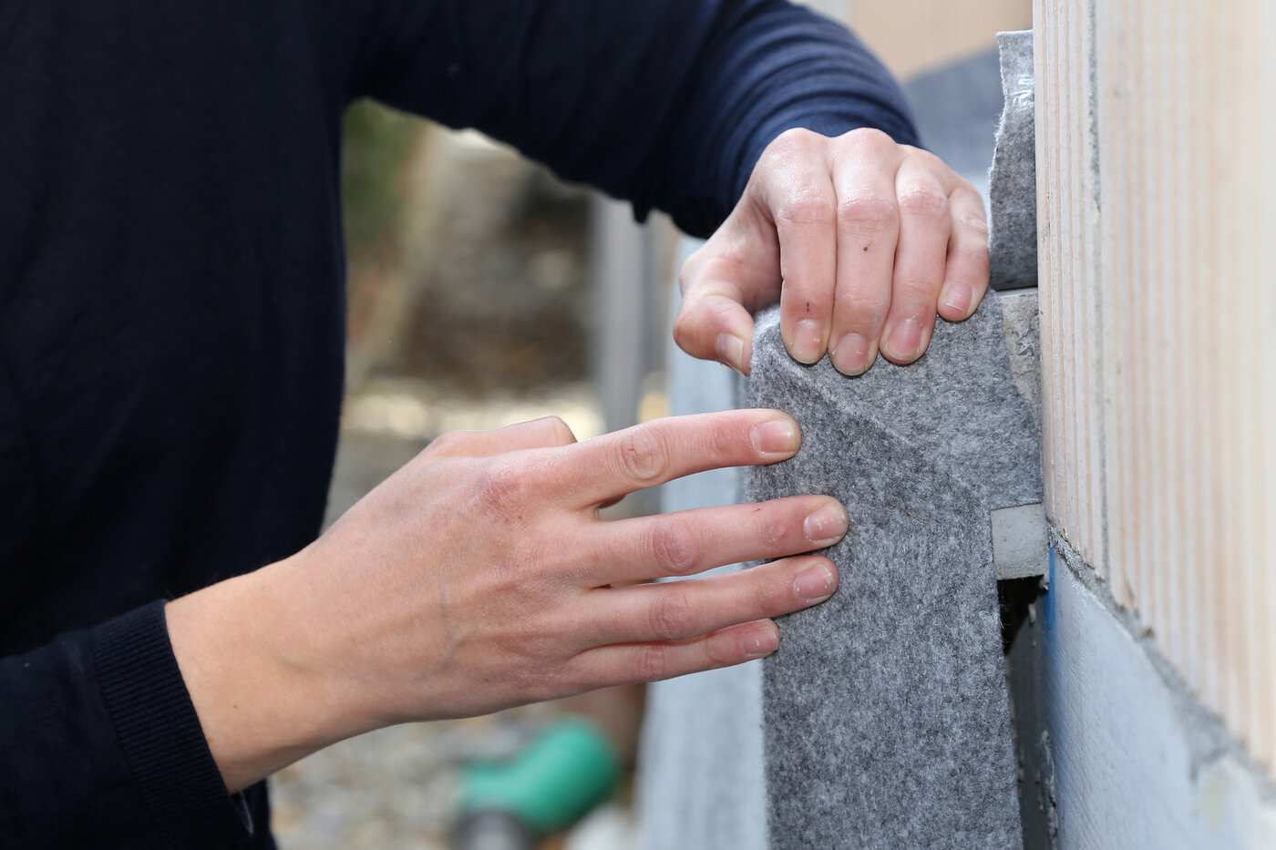 Eine Arbeiterin zeigt die Anwendung vom Schutzvlies Allfelt 1130 an einem Fenstersims.