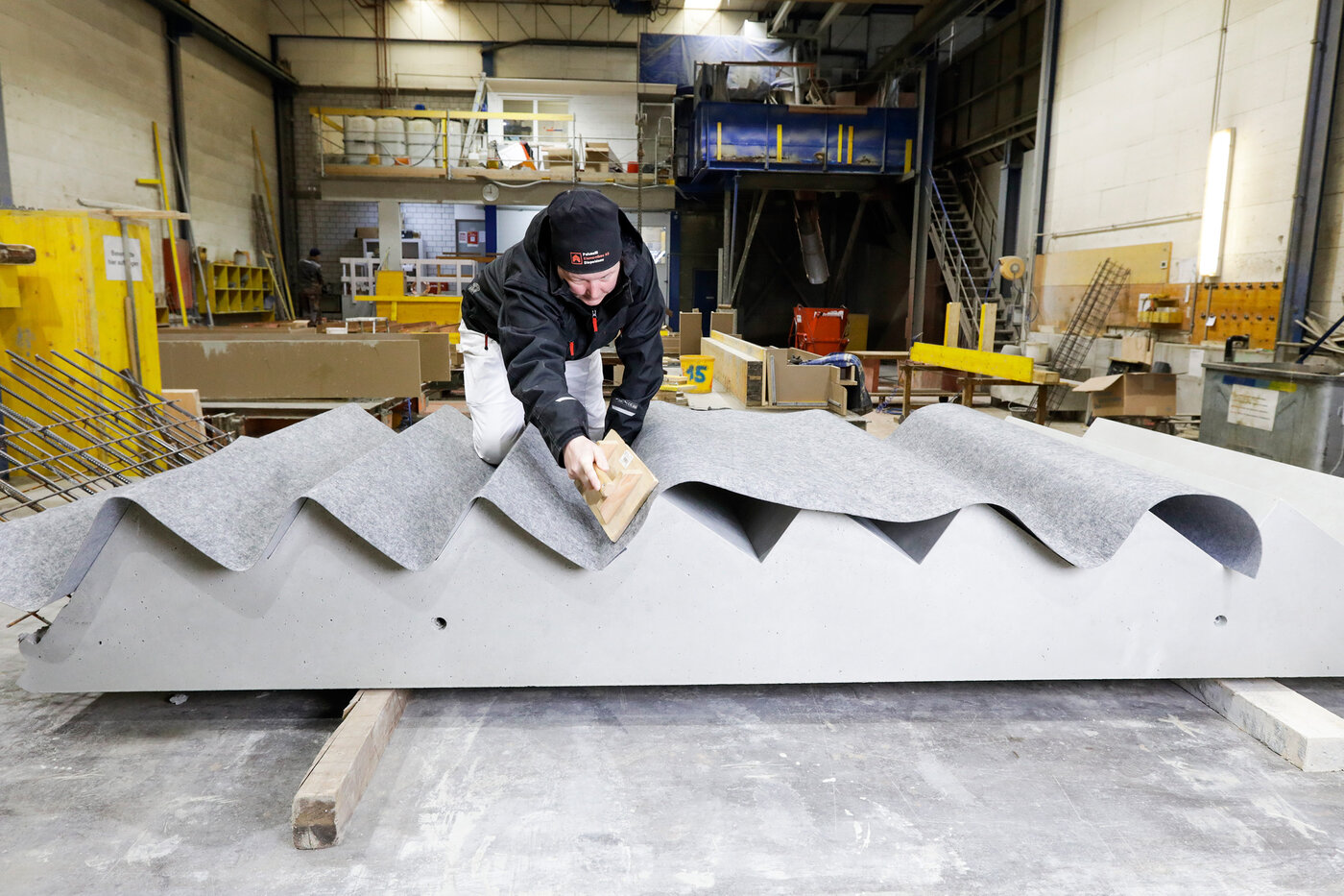 Ein Arbeiter verlegt das Schutzvlies Allfelt 1130 auf eine Treppe.