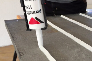 Weisser Montageklebstoff Permafix 1154 wird auf eine Platte aufgetragen