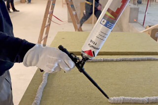 Arbeiter spritzt Permafix 1166 Klebstoffschaum auf eine Dämmplatte auf.