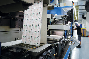 Grosse Druckmaschine mit bedrucktem Tubenlaminat.