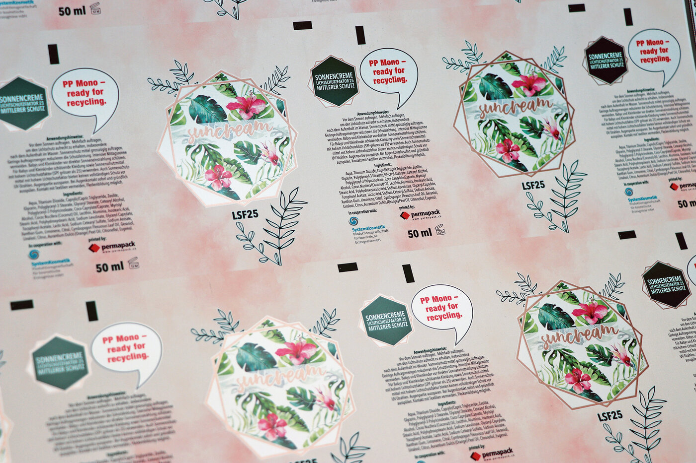 Ausschnitt von bedrucktem Tubenlaminat mit Blumenmuster, Sprechblase und Text.