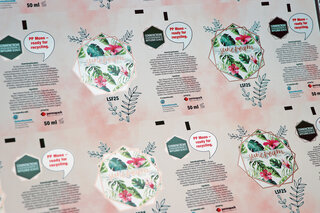Ausschnitt von bedrucktem Tubenlaminat mit Blumenmuster, Sprechblase und Text.