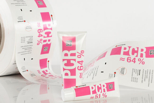 Zwei PCR-Tuben in verschiedenen Grössen mit einer Rolle Tubenlaminat im Hintergrund.