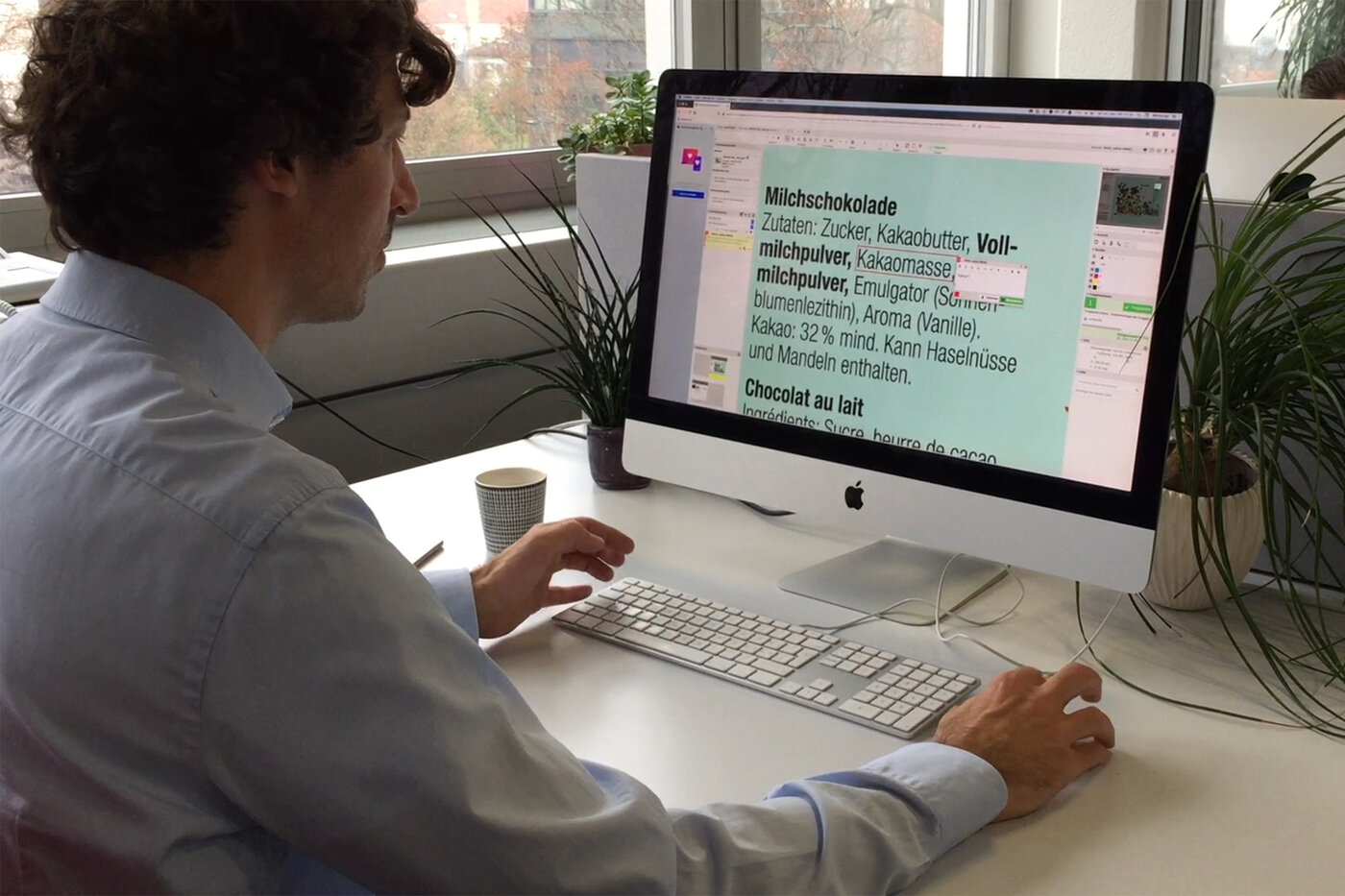 Ein Mann sitzt vor einem grosse Computerbildschirm und markiert einen Text