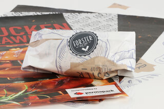 Muster von bedruckten Fleischwickelfolien und ein in eine Folie eingepacktes Stück Fleisch.