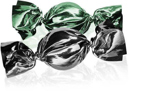 Zwei Bonbons, der vordere Bonbon hat eine schwarze Verpackung. Der hintere hat eine grüne Verpackung. 