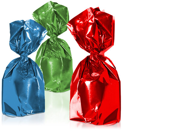 Drei Pralinen, verpackt in einer blauen, einer grünen und einer roten glänzenden Twistfolie. 
