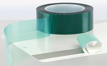 Auf einer Metallplatte wurde ein Streifen mit einem Elektroklebeband während des Pulverbeschichten abgedeckt. Unter dem zum Teil abgezogenen Elektroband sieht man die ursprüngliche graue Farbe. 