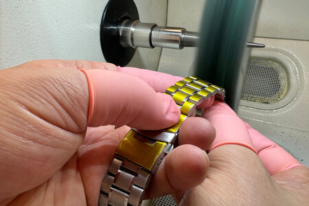 Ein Uhrenarmband ist mit einer Oberflächenschutzfolie als Formstanzteil abgedeckt und wird poliert.