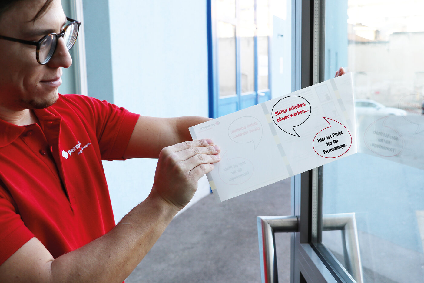 Mann klebt eine Fensteretikette auf eine Türscheibe.
