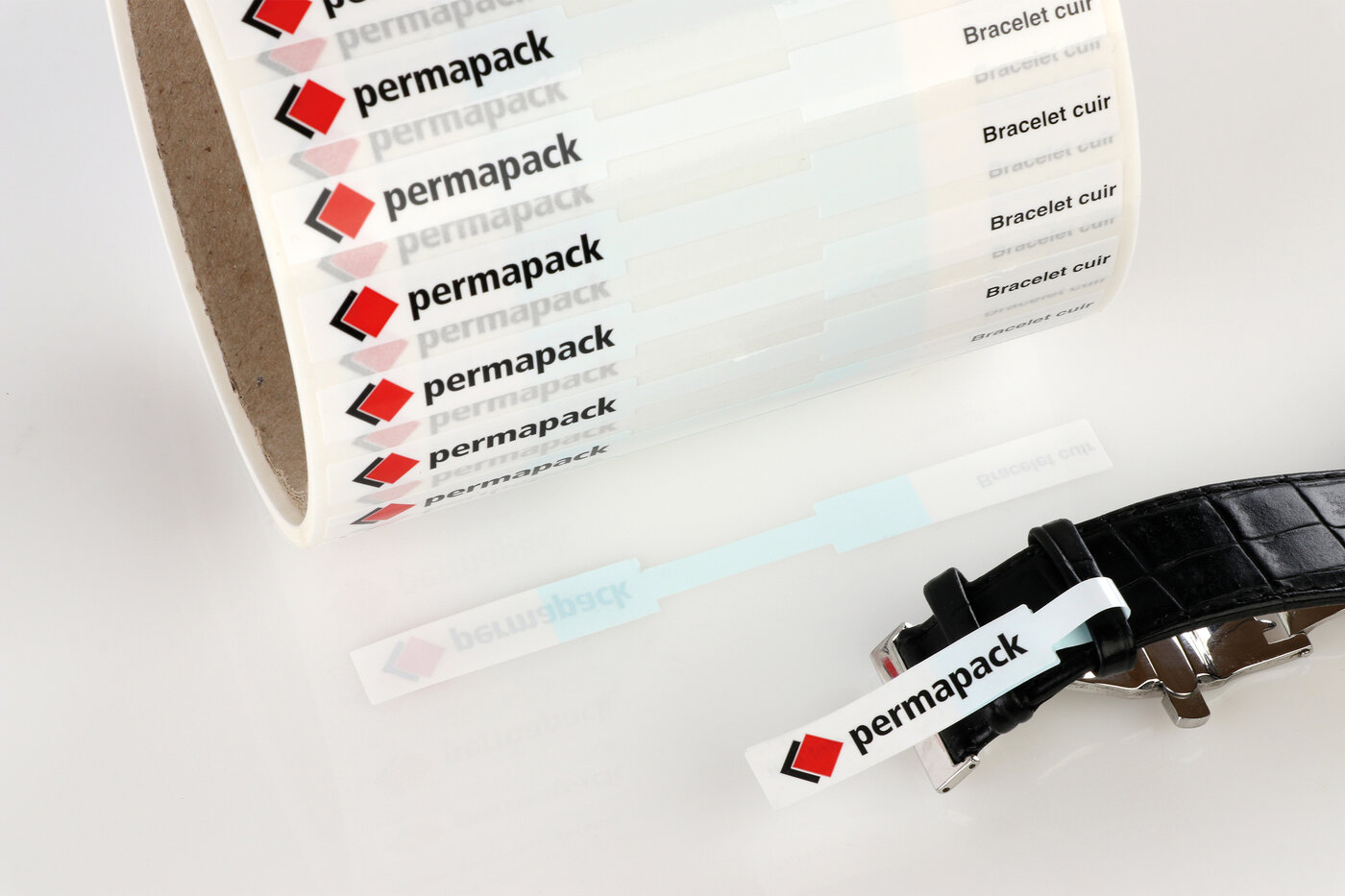 Etiketten mit nicht klebenden Zonen auf einer Rolle und einem Uhrenarmband.