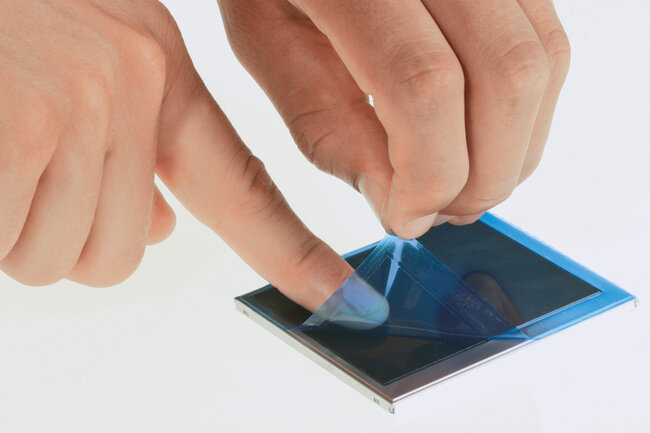 Blaue Schutzfolie wird von einem kleinen Display gezogen