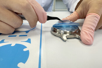 Blaue Schutzfolie wird auf ein Uhrenglas aufgebracht.