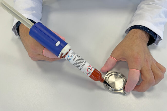 Ein Uhrenglas wird in ein Uhrengehäuse mit flüssigem UV-Klebstoff permanent eingeklebt.