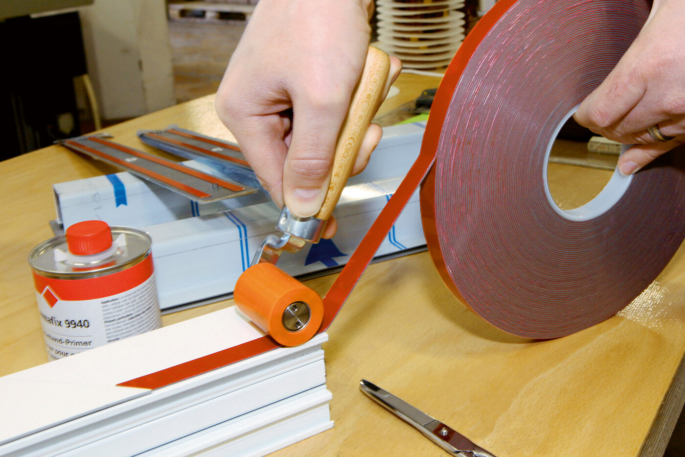 Klebeband wird mit einem Anpressroller auf ein Kunststoffteil angepresst. 