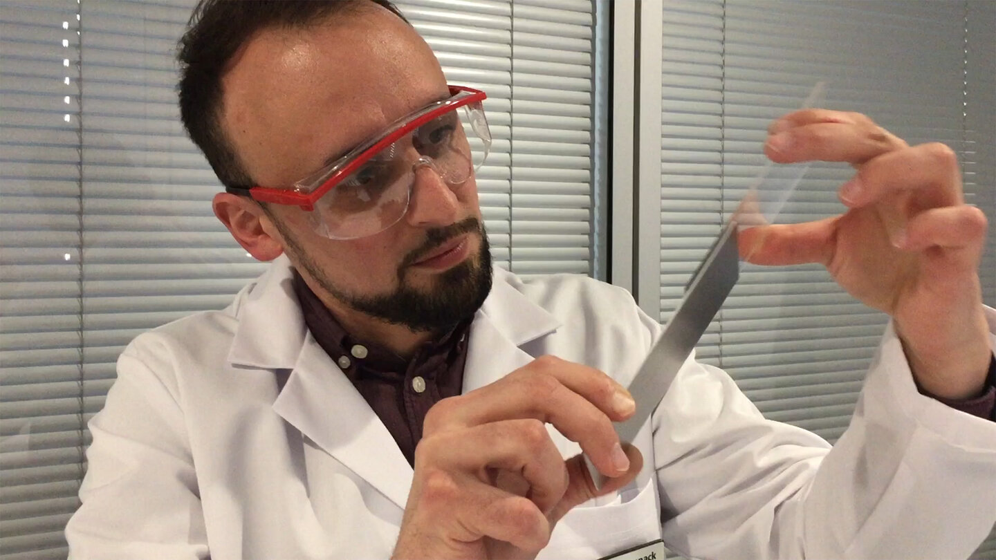 Mitarbeiter kontrolliert UV-Verklebung zwischen einem Metall- und einem Glasstück.