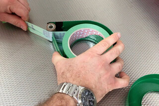 Mann setzt Klebebandrolle in Abroller ein