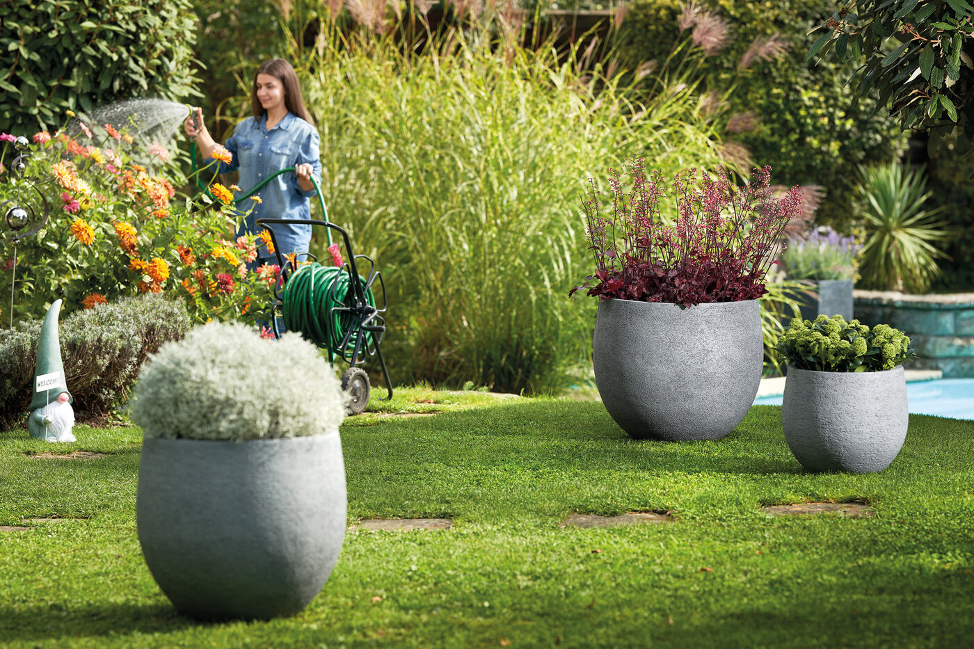 Graue runde Pflanzengefässe in unterschiedlichen Grössen im Garten