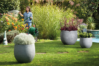 Graue runde Pflanzengefässe in unterschiedlichen Grössen im Garten