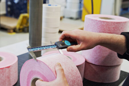 Hand mit einer Schublehre, die die Breite eines Dichtbandes misst.