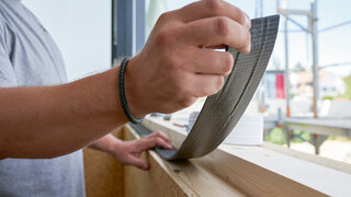 Arbeiter appliziert Abdichtband auf Fenstersims