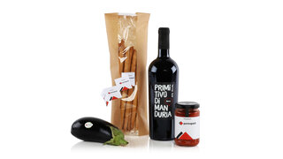 Ein Ensemble mit einer Aubergine, einem Beutel mit Knabberstengeln, einer Flasche Wein und einem Glas versehen mit bedruckten Etiketten.