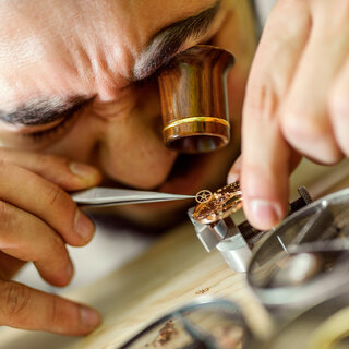 Uhrenmacher mit Lupe bei der Arbeit. 