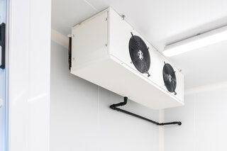 An der Decke hängt eine grosse, weisse Kühlzelle. 