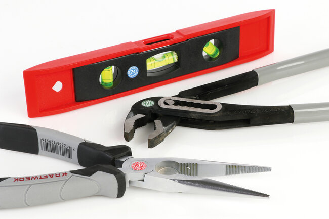 Zwei Zangen und eine Wasserwaage beklebt mit Serviceetiketten. 