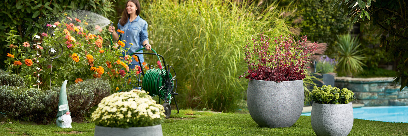 Graue runde Pflanzengefässe in unterschiedlichen Grössen im Garten