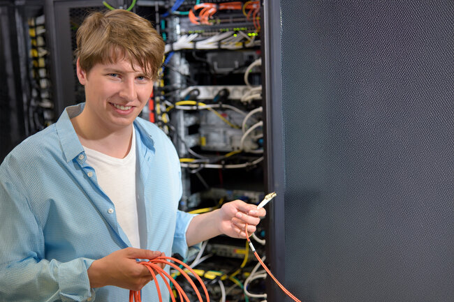 Lernender Informatiker vor einem Serverschrank